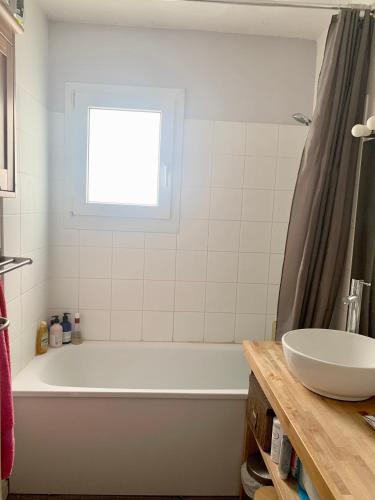 une salle de bain avec une baignoire, un lavabo et une fenêtre dans l'établissement Appartement calme avec jardin, à Bruges