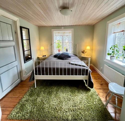 1 Schlafzimmer mit einem Bett mit einem Teppich und 2 Fenstern in der Unterkunft Stuga i Vallebygden, Axvall in Axvall