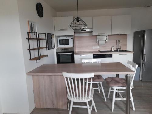 - une cuisine avec une table en bois et des chaises blanches dans l'établissement Daxou, à Dax