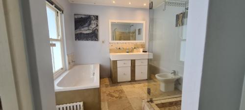 Un baño con bañera, lavabo e inodoro. en Beach House on 5th Hermanus, en Hermanus