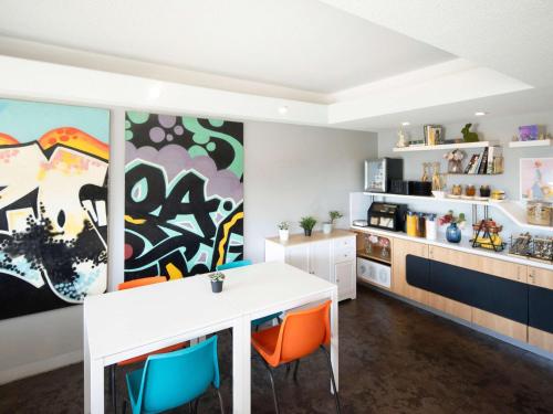 a kitchen with a white desk and orange chairs at ibis Budget Wentworthville in Wentworthville