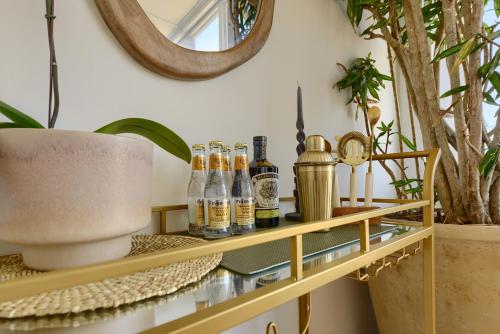 a shelf with bottles on it with a mirror at Stoep By Ideas Cartel in Kalk Bay