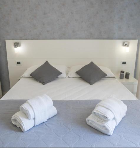 a large white bed with two towels on it at Rimini Bay Suites&Residence in Rimini