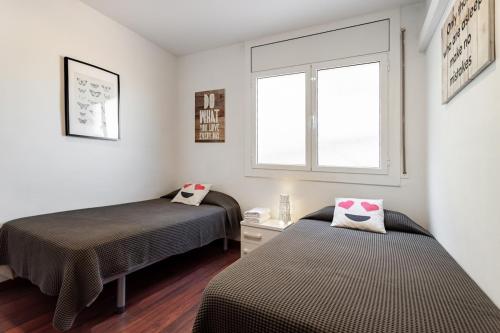 two beds in a small room with a window at Camp nou Apartamento in Hospitalet de Llobregat