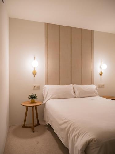a bedroom with a white bed and a small table at Hotel Oriente in Zaragoza