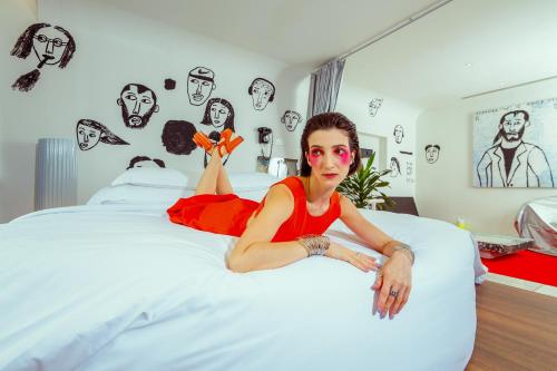 a woman laying on a bed with drawings on the wall at The Fig Lobby Bangkok in Bangkok