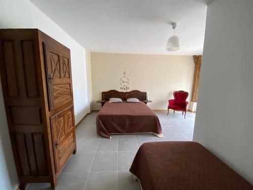 une chambre avec un lit et une chaise rouge dans l'établissement La grange des plagnettes, à Montpezat-de-Quercy