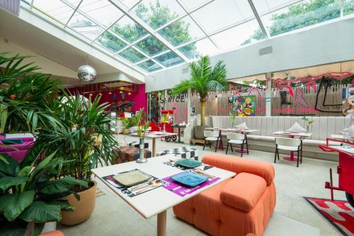 a restaurant with an orange couch and tables and plants at The Fig Lobby Bangkok in Bangkok