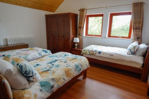 a bedroom with two beds and two windows at Tullynore Villa in Hillsborough