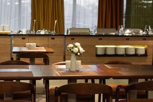 a table with a vase of flowers on it at Almaty Hotel in Almaty