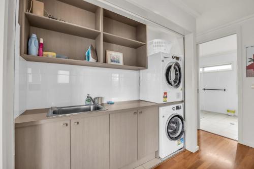 a kitchen with a sink and a washing machine at Haven on the Headland in Merimbula