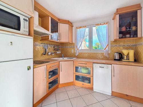 une cuisine avec des armoires en bois et un réfrigérateur blanc dans l'établissement VILLA PROCHE MER ET MONTAGNE - Vacances sans voiture, à Argelès-sur-Mer