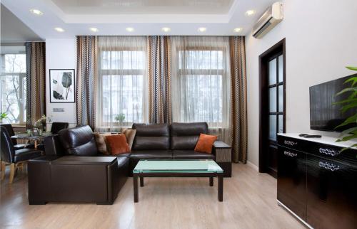 a living room with a black leather couch and a tv at Apartment & Parking "Opera at the corner" in Odesa