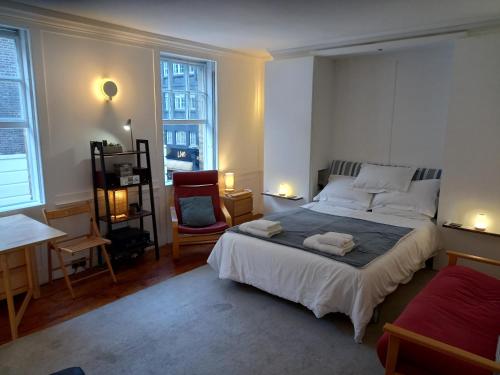 a bedroom with a large bed and a chair at Large Bright Soho Studio flat with Large Terrace in London