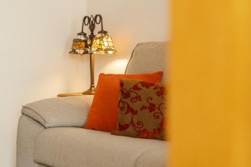 a gray couch with an orange pillow and a lamp at La Sultana de Vejer in Vejer de la Frontera