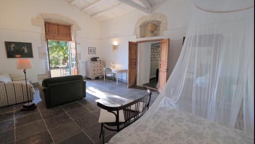 a living room with a bed with a mosquito net at Case Brizza in Casale Zappulla