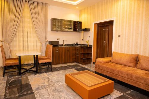 a living room with a couch and a table and a kitchen at Number Ten by Scarborough - Luxury Serviced Apartments, Asaba in Asaba