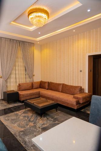 a living room with a brown couch and a chandelier at Number Ten by Scarborough - Luxury Serviced Apartments, Asaba in Asaba
