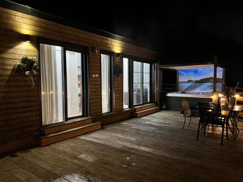 a wooden deck with a table and chairs and windows at Burtree Country House, Tipi's, Treehouse & Lodge & house rooms with hot tubs in a private garden in Thirsk