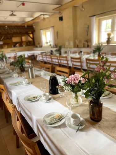 a long table with white table cloth and flowers on it at Landkulturhof Glücksbringer in Rudolstadt