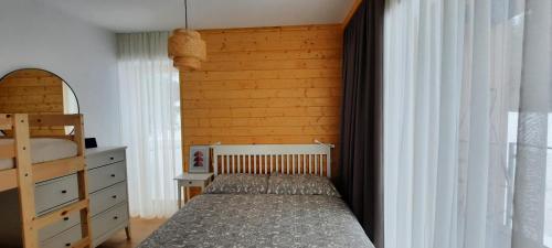 a bedroom with a bed and a wooden wall at Villa Erdődy Resort - Apartman 18 in Oravská Lesná