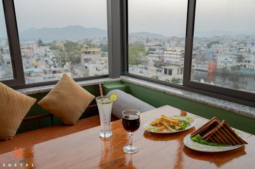 uma mesa com dois pratos de comida e um copo de vinho em Zostel Udaipur em Udaipur