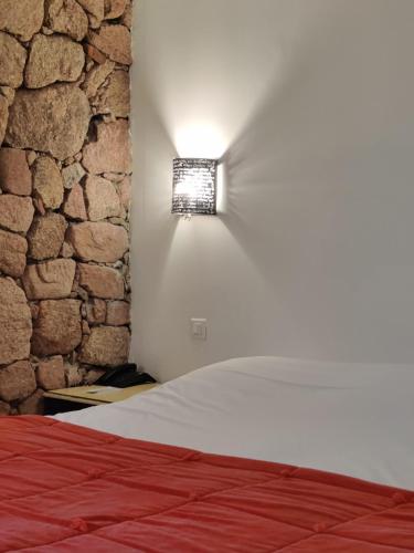 a bedroom with a bed and a stone wall at Le Roc E Fiori Hotel - Teritoria in Porto-Vecchio