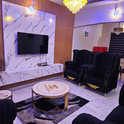 a living room with couches and a flat screen tv at Hansville Apartment in Benin City