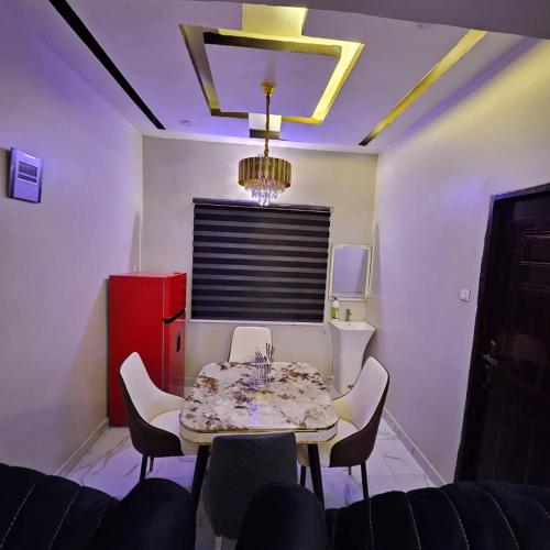 a dining room with a table and chairs and a chandelier at Hansville Apartment in Benin City