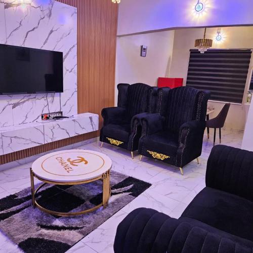 a living room with couches and a tv and a table at Hansville Apartment in Benin City