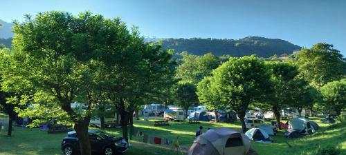 un camping avec des tentes et une voiture garée dans l'herbe dans l'établissement Camping Onlycamp Les Adoubes - Albertville, à Albertville