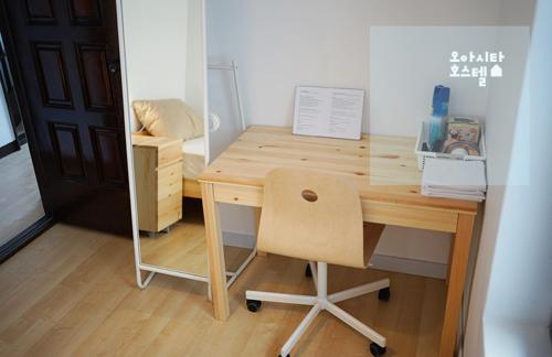 a wooden desk with a chair in a room at Oasita Hostel in Gwangju