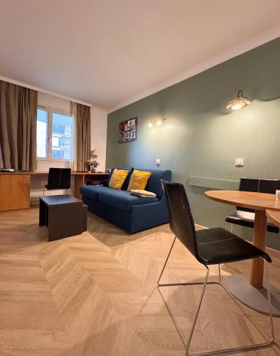 un salon avec un canapé bleu et une table dans l'établissement Cosy Appartement 2P avec Balcon Paris La Défense Parking Gratuit, à Courbevoie