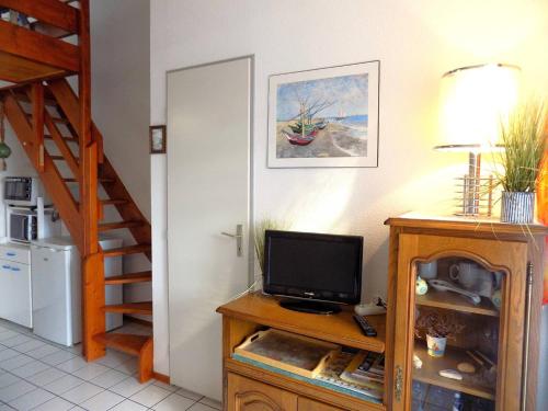 Cette chambre dispose d'une télévision sur un support en bois avec un escalier. dans l'établissement Saint Palais sur Mer - VILLA MITOYENNE de VACANCES - résidence BOIS SOLEIL, à Puyraveau