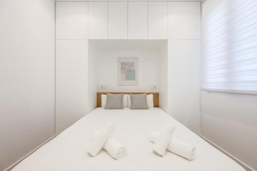- une chambre blanche avec un grand lit blanc et 2 oreillers dans l'établissement Urban Tranquility in Madrid with Modern Comforts, à Madrid