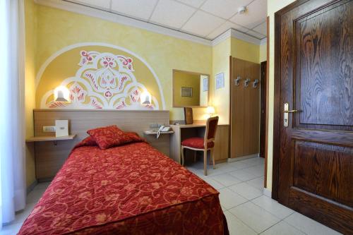 a bedroom with a bed and a desk and a door at Stella Alpina Hotel e Ristorante in Druogno