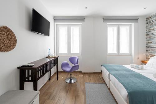 a bedroom with a bed and a desk and a purple chair at AL-Odeceixe Verde in Odeceixe