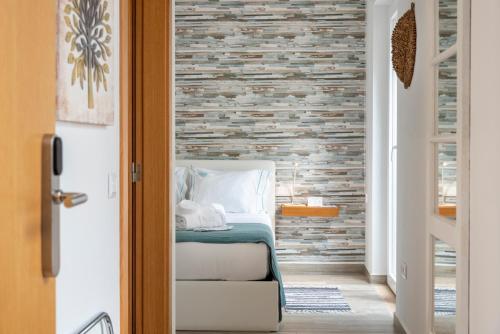 a bedroom with a bed and a brick wall at AL-Odeceixe Verde in Odeceixe