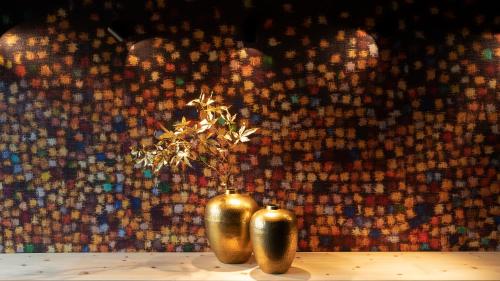 two gold vases with a plant in them on a table at Hotel Europa Suites St Moritz in St. Moritz