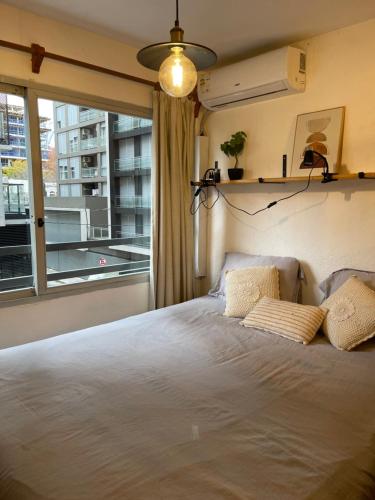 a bedroom with a bed and a large window at Comodo monoambiente bien ubicado en Cordon in Montevideo