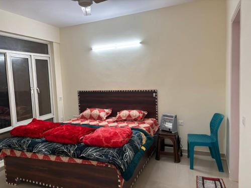a bedroom with a bed with red pillows and a blue chair at Omaxe Ananda in Prayagraj