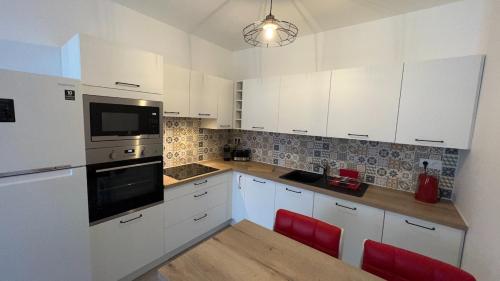 a kitchen with white cabinets and a table with red chairs at Magnifique 2p cœur historique in Auray