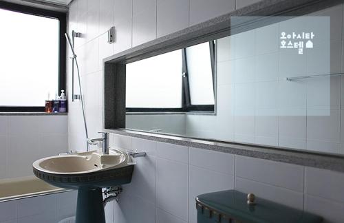 a bathroom with a sink and a mirror at Oasita Hostel in Gwangju
