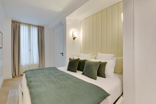 une chambre avec un grand lit blanc avec des oreillers verts dans l'établissement Pick A Flat's apartment in Opéra- Rue Lafitte, à Paris