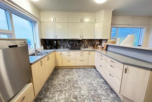 a large kitchen with white cabinets and counters at House in Fjörður in Lón South East of Iceland - Birta Rentals in Höfn