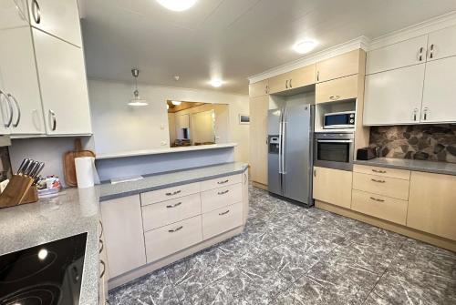 a kitchen with white cabinets and stainless steel appliances at House in Fjörður in Lón South East of Iceland - Birta Rentals in Höfn