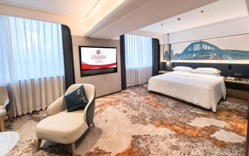 a bedroom with a bed and a chair and a tv at Hotel Landmark Canton in Guangzhou