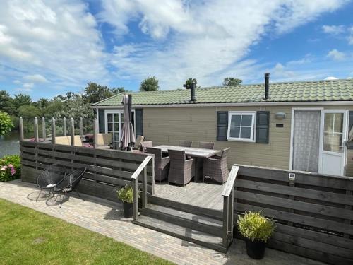a deck with a table and chairs and a house at Chalet Makkum C99B met prive gelegen tuin aan het water in Makkum