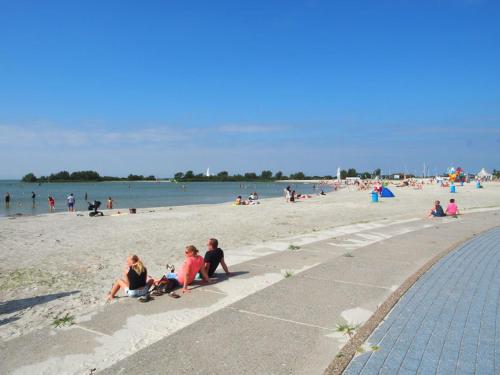 a group of people sitting on the beach at Chalet Makkum C99B met prive gelegen tuin aan het water in Makkum