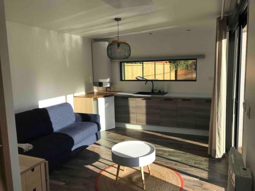 un salon avec un canapé bleu et une table dans l'établissement Guest House avec piscine et jardin Privatifs, à Le Pian-Médoc